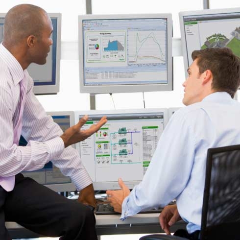 使用施耐德电气监控软件在显示器前查看可持续发展报告、大数据分析的商务男士。