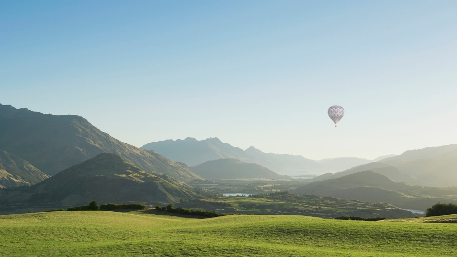 hot air balloon flying over green mountains