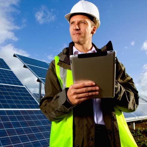 工程师站在太阳能面板前，使用数字平板电脑进行能源管理。