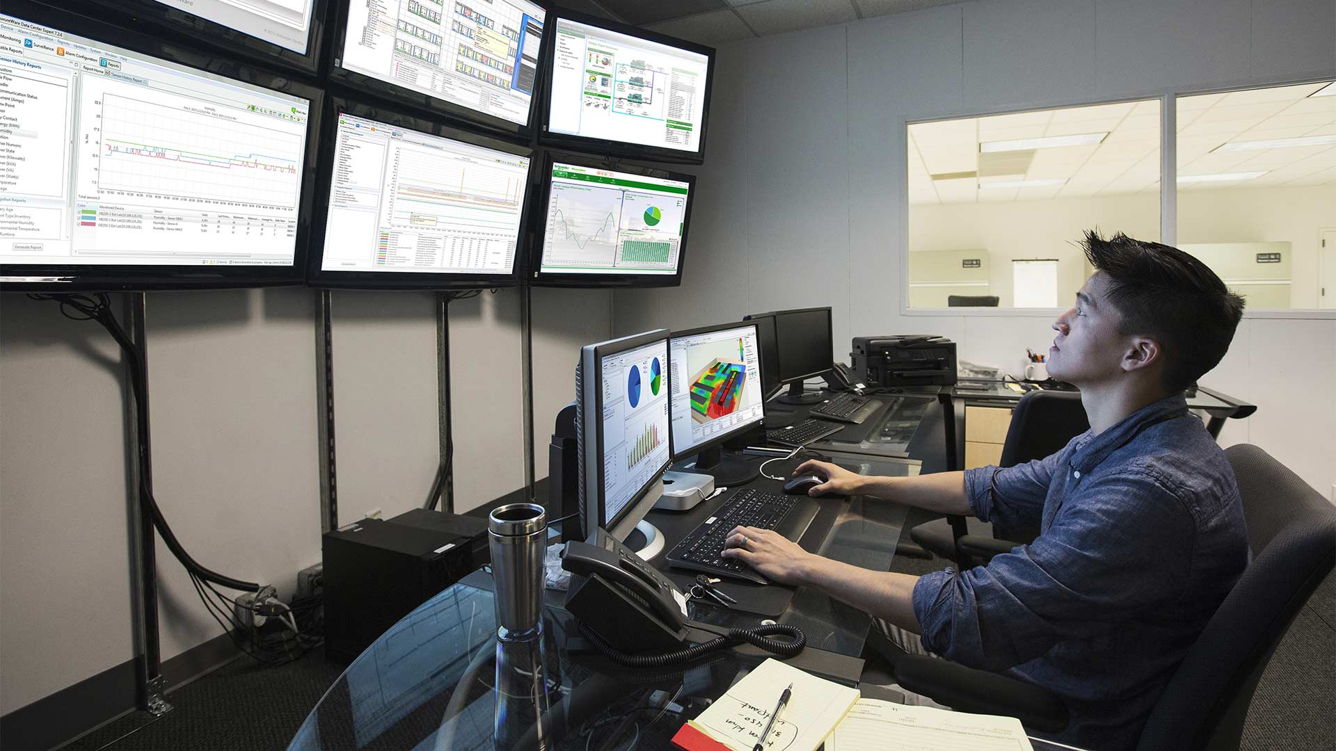 Employee working at a control room with many screens in front