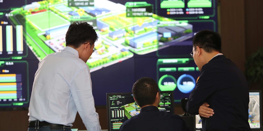 People discussing inside a control room with big screens