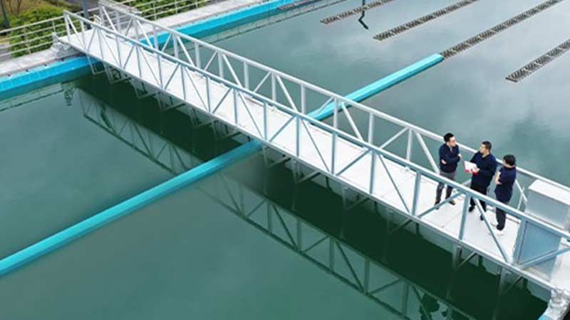Three employees discussing while standing on a bridge at a water treatment facility